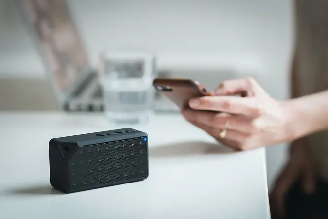 Person holding smartphone near to a Bluetooth speaker