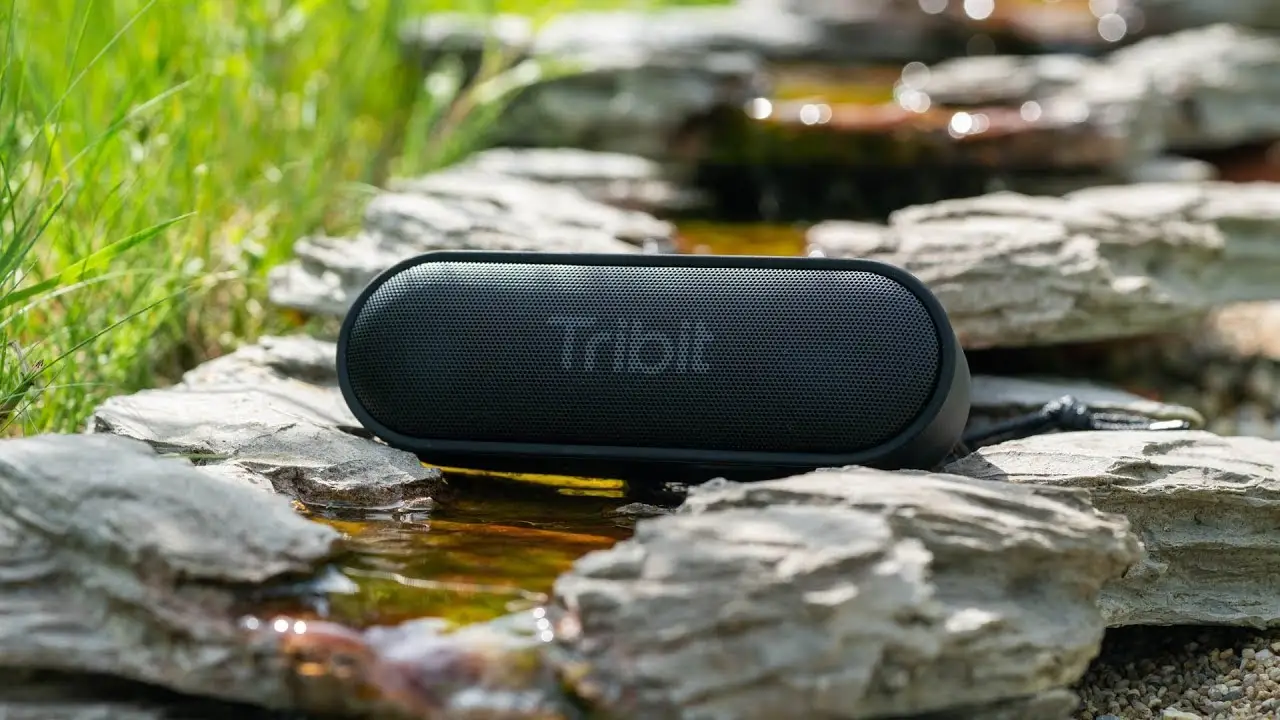 Tribit Bluetooth speaker placed outside in small trickling stream.