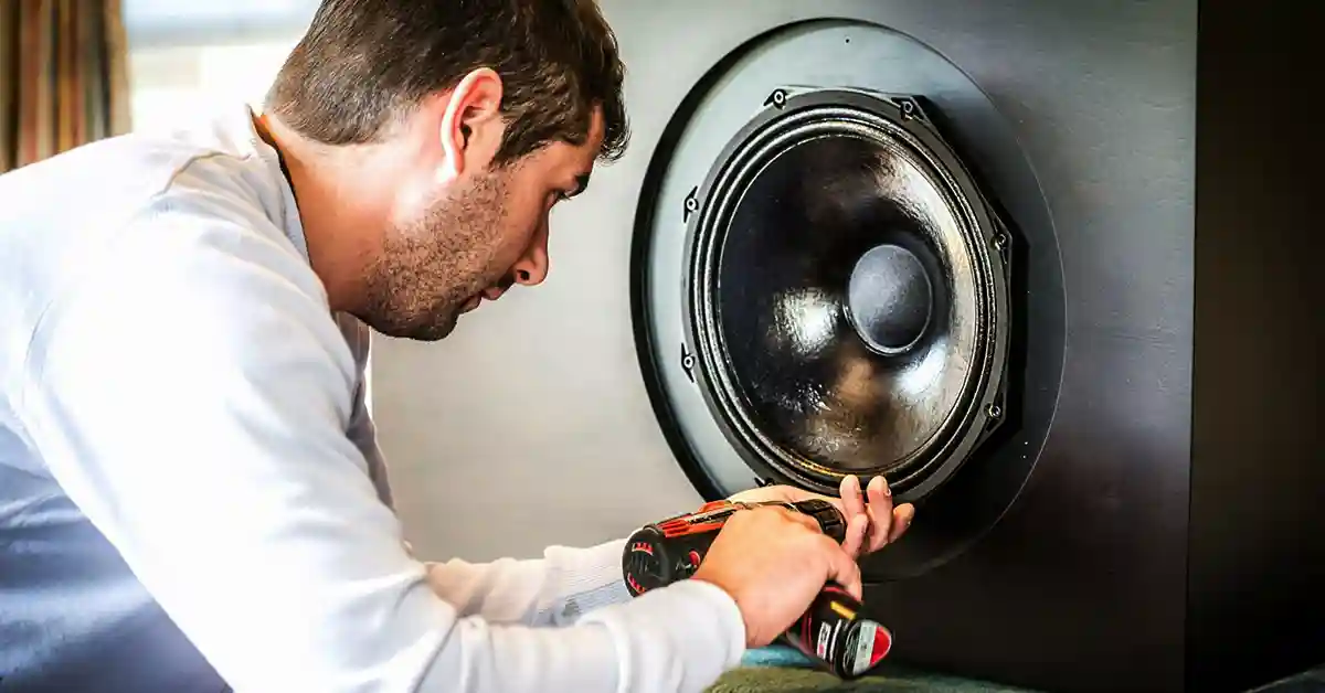 Man repairing speakers with a screwdriver